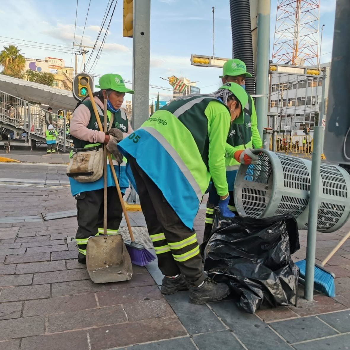 Personal de limpieza recoge la basura de un cesto en una esquina de la ciudad.