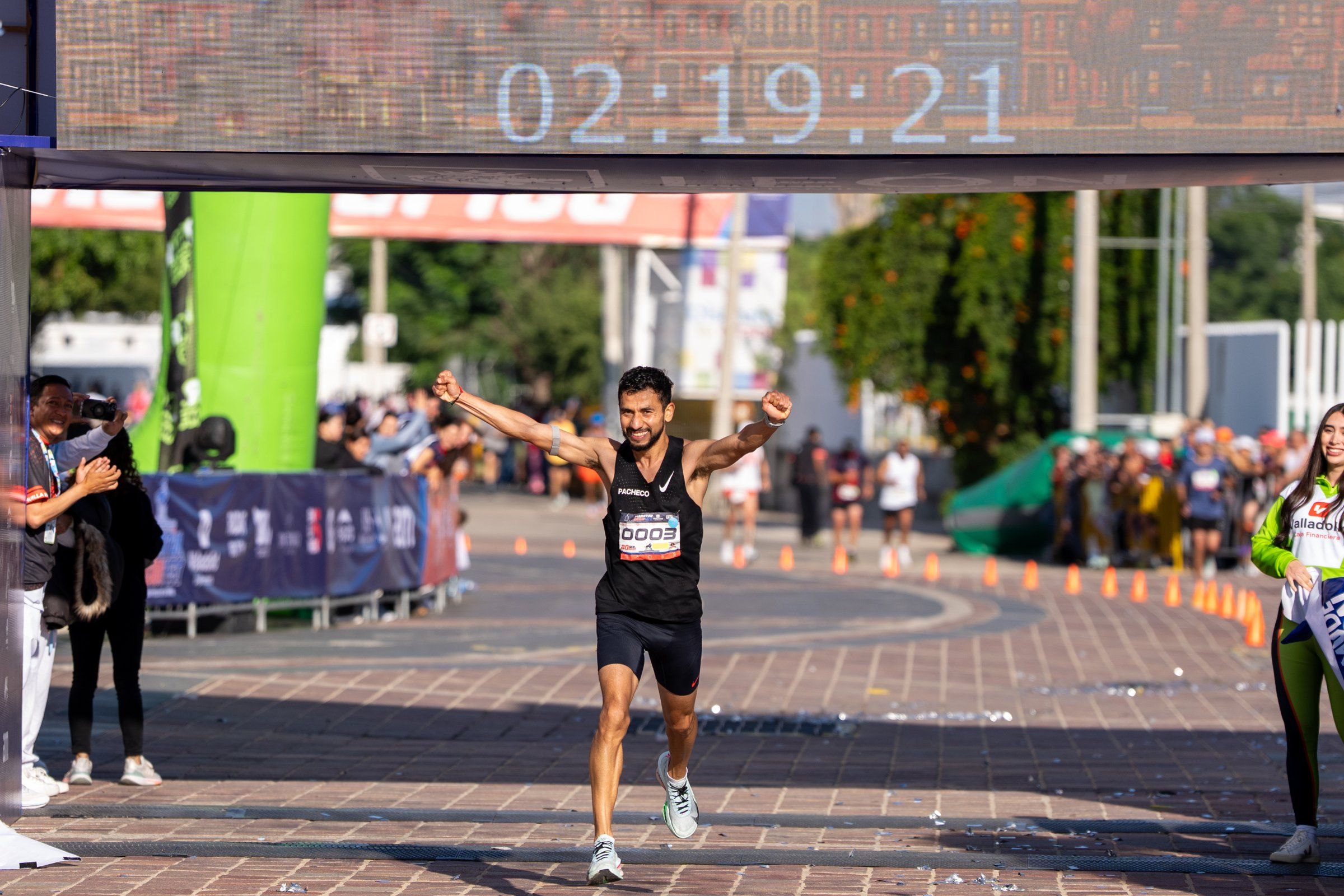 Un corredor llega a la meta del Maratón León 450 con los brazos en alto.